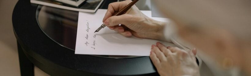 A person writing a letter at a desk, illustrating an authentic donation thank-you letter