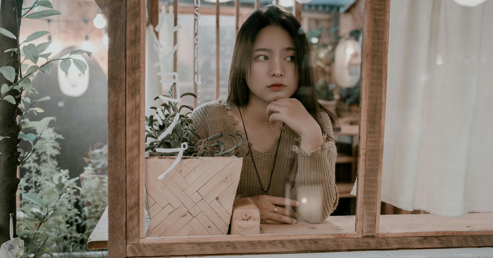 Young woman resting her chin on her hand and gazing sideways in a cafe, conveying quiet scepticism