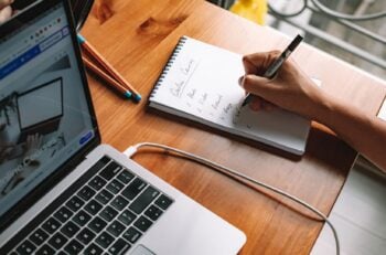 Laptop showing an online courses website next to a notepad listing course ideas