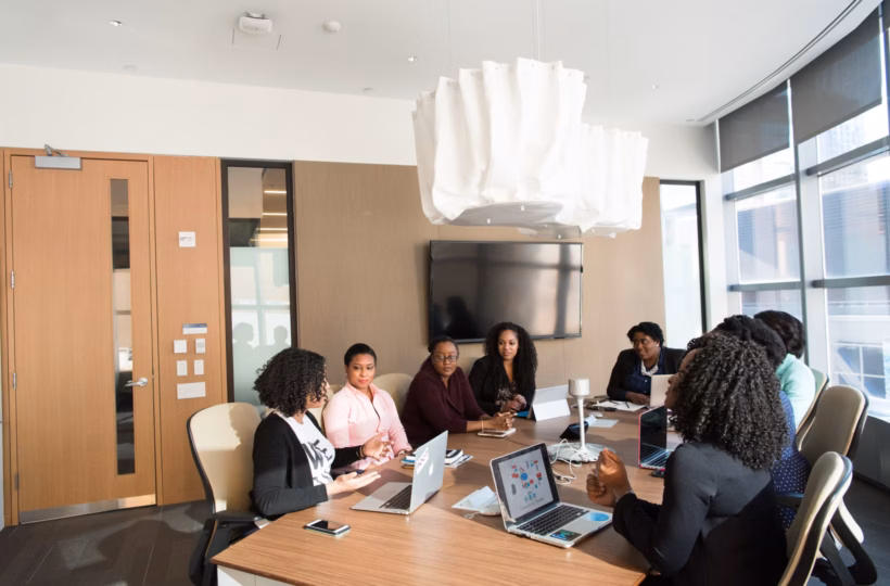 A nonprofit board of directors meeting around a conference table in a bright boardroom