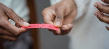 Two people handing over a red paper event ticket