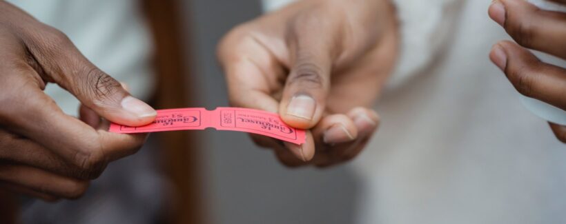 Handing over a paper ticket, representing selling event tickets on a WooCommerce store